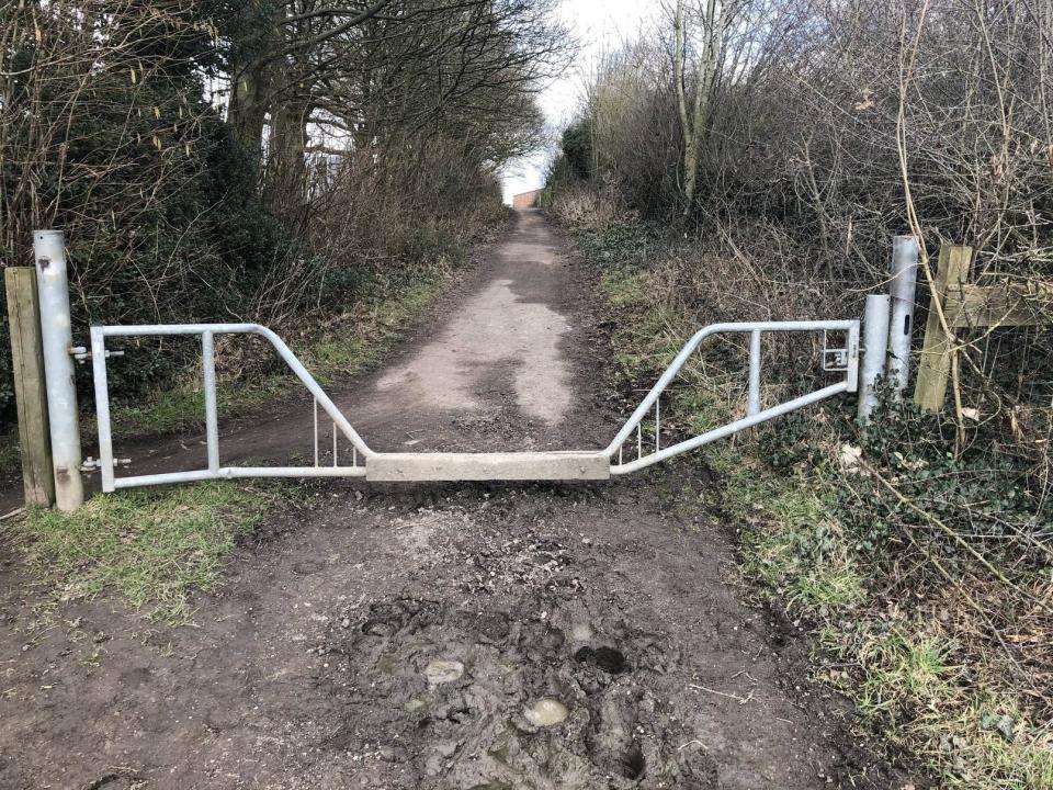 a metal gate that has a dip in the middle for horses to step over but is not wide enough for a vehicle