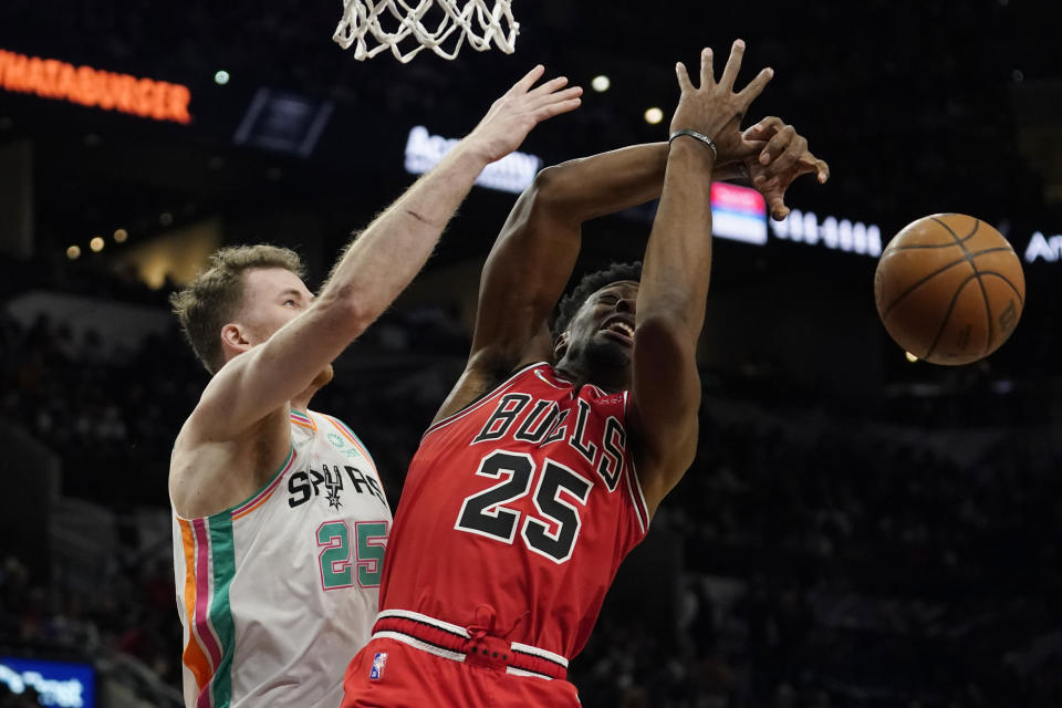 San Antonio Spurs center Jakob Poeltl, left, and Chicago Bulls forward Tyler Cook, right, scramble for a rebound during the first half of an NBA basketball game, Friday, Jan. 28, 2022, in San Antonio. (AP Photo/Eric Gay)