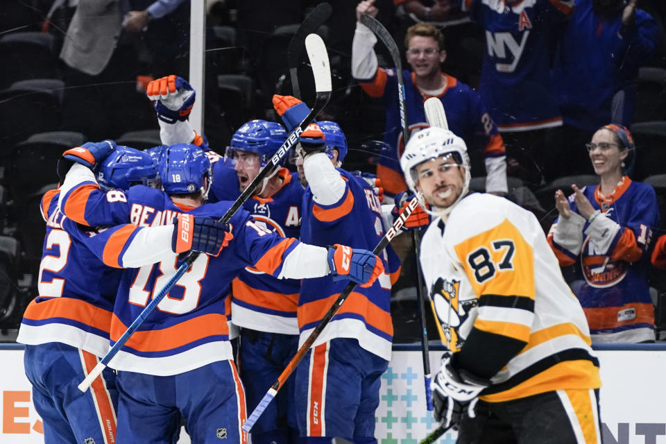 New York Islanders' Brock Nelson celebrates with teammates after scoring a goal as Pittsburgh Penguins' Sidney Crosby (87) skates past them during the second period of Game 6 of an NHL hockey Stanley Cup first-round playoff series, Wednesday, May 26, 2021, in Uniondale, N.Y. (AP Photo/Frank Franklin II)