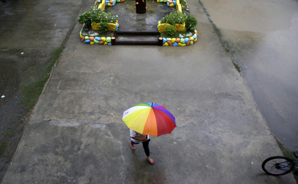 A resident walks as rains from Typhoon Mangkhut begin to affect Tuguegarao city, Cagayan province, northeastern Philippines on Friday, Sept. 14, 2018. Typhoon Mangkhut retained its ferocious strength and slightly shifted toward more densely populated coastal provinces on Friday as it barreled closer to the northeastern Philippines, where a massive evacuation was underway. (AP Photo/Aaron Favila)