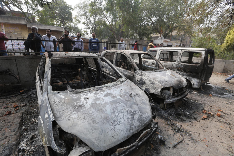 People look at cars that were vandalized during violence in New Delhi, India, Wednesday, Feb. 26, 2020. At least 20 people were killed in three days of clashes in New Delhi, with the death toll expected to rise as hospitals were overflowed with dozens of injured people, authorities said Wednesday. The clashes between Hindu mobs and Muslims protesting a contentious new citizenship law that fast-tracks naturalization for foreign-born religious minorities of all major faiths in South Asia except Islam escalated Tuesday. (AP Photo/Rajesh Kumar Singh)