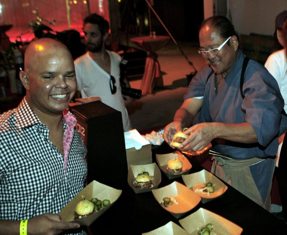 Chef Masaharu Morimoto, right, works on his WagyuBurger while competing in the Burger Bash at the Food Network South Beach Wine & Food Festival in Miami Beach, Fla., Friday, Feb. 24, 2012. (AP photo/Jeffrey M. Boan)