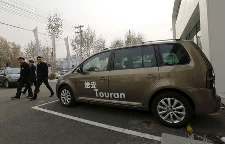 Salesmen walk past a VW Touran mini-van outside an automobile showroom in Beijing, China, November 27, 2015. REUTERS/Jason Lee