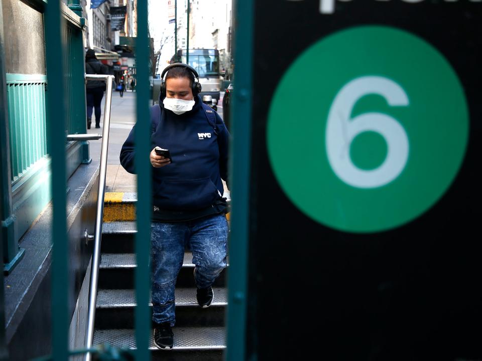 coronavirus covid 19 bluetooth headphones mobile phone man face mask commuting walking down stairs subway train mta new york city nyc GettyImages 1216307933