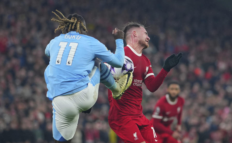 CAPTION CORRECTS PLAYER ID ON THE RIGHT Manchester City's Jeremy Doku, foreground, and Liverpool's Alexis Mac Allister fight for the ball during the English Premier League soccer match between Liverpool and Manchester City, at Anfield stadium in Liverpool, England, Sunday, March 10, 2024. (AP Photo/Jon Super)