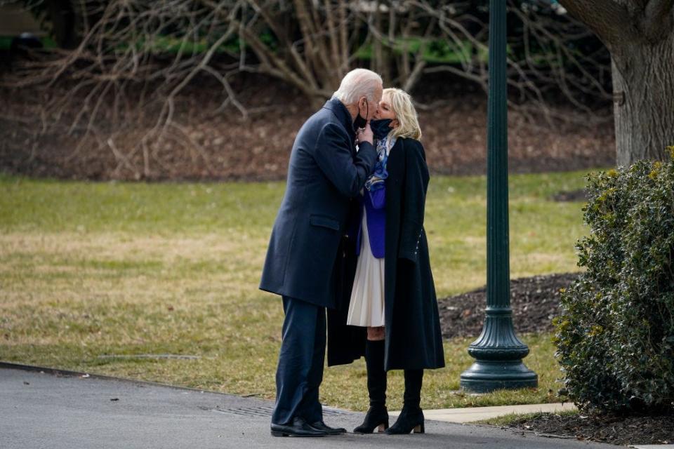 President Joe Biden lowers his mask to kiss wife Jill Biden as he walks to Marine One on the South Lawn of the White House for a trip to Walter Reed medical center to visit with wounded service members on Jan. 29, 2021.