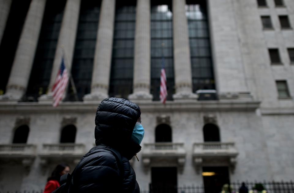 A woman with a facial mask passes the New York Stock Exchange (NYSE) on February 3, 2020 at Wall Street in New York City. - Wall Street stocks rose early Monday, bouncing after Friday's rout as markets monitored the coronavirus at the start of a week with key economic data and earnings reports. The Dow suffered the worst losses of the year on Friday as the death toll from the virus continued to climb and the ailment spread to additional countries. (Photo by Johannes EISELE / AFP) (Photo by JOHANNES EISELE/AFP via Getty Images)