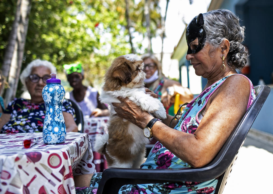 An elderly woman holds a dog named Cristal at the "Casa de Repouso Laços de Ouro" nursing home in Sepetiba, Brazil, Thursday, Oct. 1, 2020. The Golias organization brought the animals, who they rescued from abandonment, to provide a little relief from the isolation many elderly people feel, cut off from friends and family due to fear of contagion from the new coronavirus. (AP Photo/Bruna Prado)