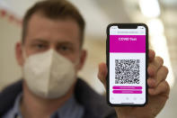 A visitor to the Corona rapid test centre at the Corona Outpatient Clinic in a sports hall shows on his mobile phone the QR code he received with the online appointment confirmation, in Koblenz, Germany, Monday, March 8, 2021. (Thomas Frey/dpa via AP)