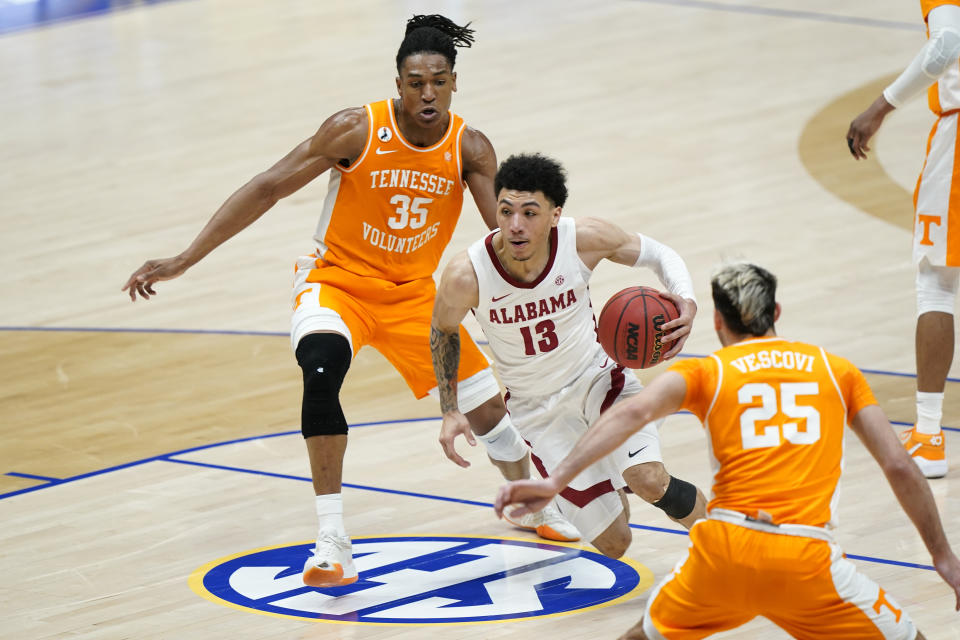 Alabama's Jahvon Quinerly (13) drives against Tennessee's Yves Pons (35) and Santiago Vescovi (25) in the first half of an NCAA college basketball game in the Southeastern Conference Tournament Saturday, March 13, 2021, in Nashville, Tenn. (AP Photo/Mark Humphrey)