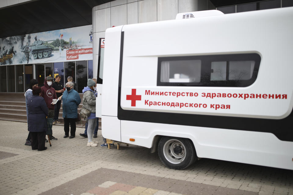 People gather to receive Russia's Sputnik V coronavirus vaccine at a mobile vaccination center in Krymsk, Krasnodar region, Russia, Friday, Oct. 29, 2021. Russia has recorded another record of daily coronavirus deaths even as authorities hope to stem contagion by keeping most people off work. Authorities have blamed soaring infections and deaths on Russia's lagging pace of vaccinations. About 51 million Russians — just over a third of the country's nearly 146 million people — were fully vaccinated as of Friday. (AP Photo/Vitaly Timkiv)