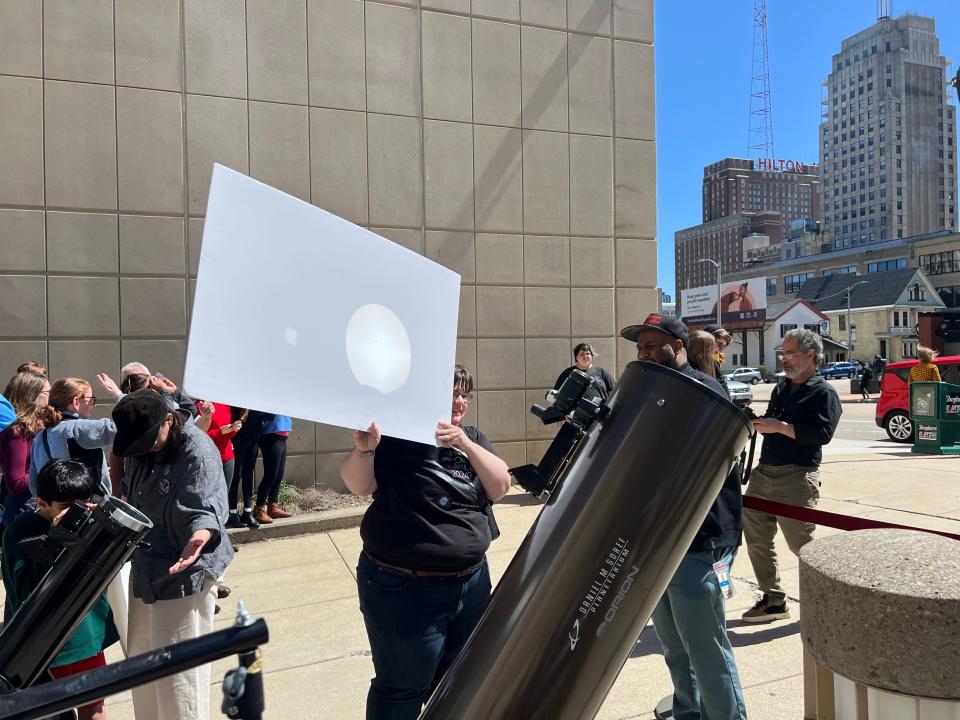 Milwaukee Public Museum planetarium educator Marshall Ward holds up a poster board so museum visitors can watch the solar eclipse.