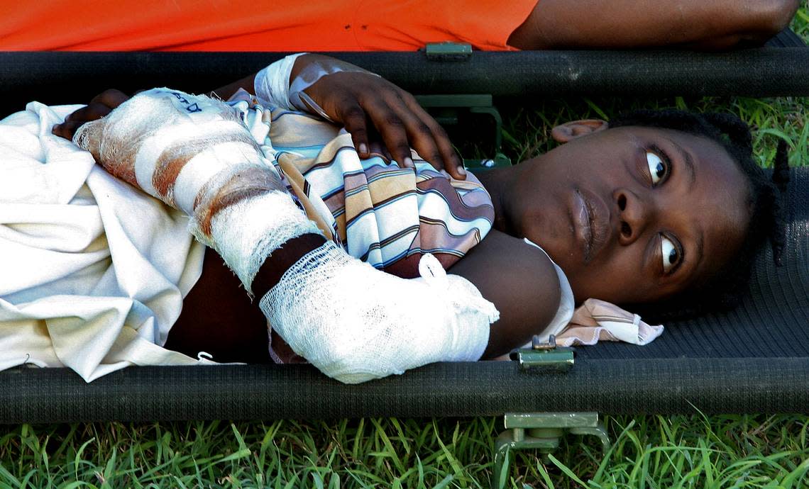 A critically injured Haitian girl watches as a US Navy helicopter approaches the lawn of the Presidential palace as she awaits evacuation.