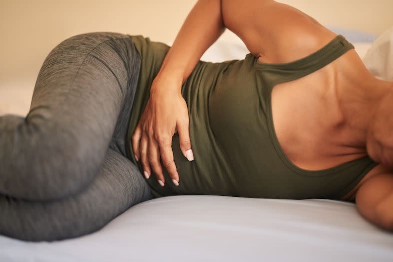 shot of a woman suffering from stomach ache on bed