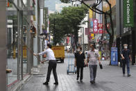 An employee wearing a face mask to help protect against the spread of the new coronavirus cleans the widows of his shoe store at a shopping street in Seoul, South Korea, Friday, June 12, 2020. (AP Photo/Ahn Young-joon)