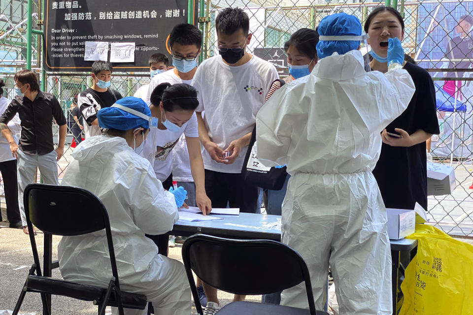 Residents line up to get tested at a coronavirus testing center set up outside a sports facility in Beijing, Tuesday, June 16, 2020. China reported several dozen more coronavirus infections Tuesday as it increased testing and lockdown measures in parts of the capital to control what appeared to be its largest outbreak in more than two months. (AP Photo/Ng Han Guan)