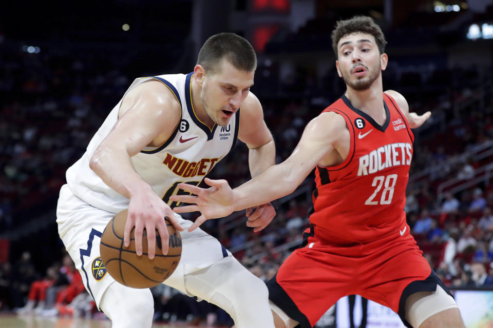 Denver Nuggets center Nikola Jokic, left, protects the ball on a drive as Houston Rockets center Alperen Sengun (28) reaches in during the first half of an NBA basketball game, Tuesday, April 4, 2023, in Houston. (AP Photo/Michael Wyke)