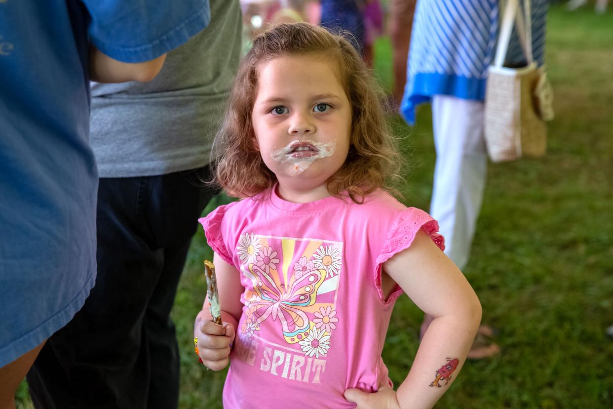 Kensley Seem, 3, of Gibsonburg, enjoys a chocolate covered pretzel at the Great Big Gibsonburg Lemonade Stand at Williams Park in Gibsonburg on Saturday.