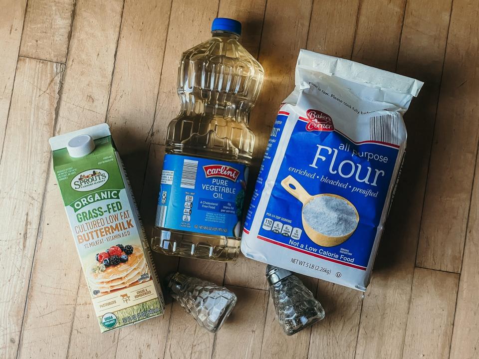 buttermilk, oil, flour, salt, and pepper on a wooden surface