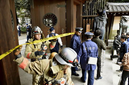 Police officers and fire fighters investigate at the south gate of Japan's controversial Yasukuni Shrine where there was an explosion and burned the ceiling and wall of the public bathroom, in Tokyo, Japan, in this photo taken by Kyodo November 23, 2015. REUTERS/Kyodo