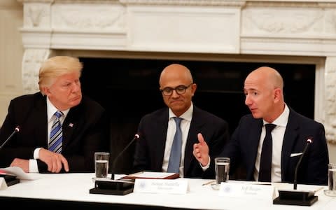 Donald Trump, left, listens to Jeff Bezos, right, speaking at a White House meeting in June 2017 - Credit: AP Photo/Alex Brandon