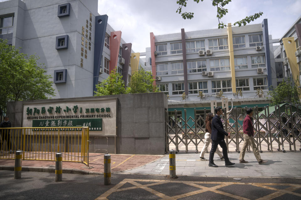 People walk past the gates of a closed primary school in Beijing, Thursday, April 28, 2022. While the U.S. and other countries are dropping restrictions and opening - with some health officials even saying the worst is over - China is keeping its international borders largely shut and closing off entire cities with millions of residents to all but essential travel. For the Chinese capital, however, the political stakes are heightened as the ruling party moves toward a crucial national congress. (AP Photo/Mark Schiefelbein)