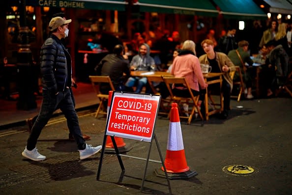 People drink at the outside tables of a cafe in Soho, in central London.