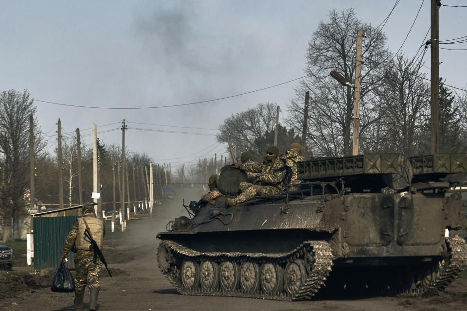 Ukrainian soldiers ride atop an APC in the heaviest battles with the Russian invaders in Bakhmut, Donetsk region, Ukraine, Sunday, April 9, 2023. (AP Photo/Libkos)