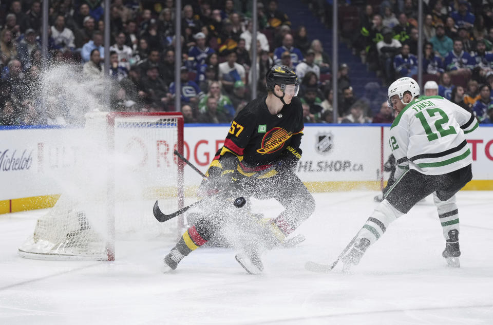 The puck deflects wide of the goal as Vancouver Canucks' Tyler Myers (57) defends against Dallas Stars' Radek Faksa (12) during the second period of an NHL hockey game Thursday, March 28, 2024, in Vancouver, British Columbia. (Darryl Dyck/The Canadian Press via AP)