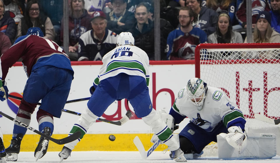 Colorado Avalanche center Ryan Johansen, left, flips the puck past Vancouver Canucks center Nils Aman, center, and goaltender Thatcher Demko for a goal in the second period of an NHL hockey game Tuesday, Feb. 20, 2024, in Denver. (AP Photo/David Zalubowski)