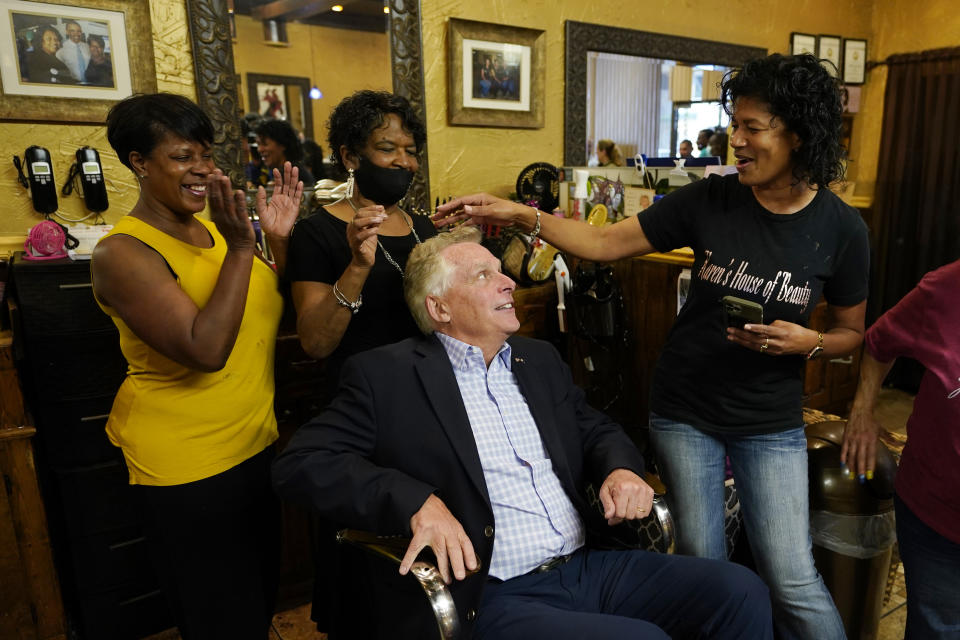 Democratic gubernatorial candidate, former Gov. Terry McAuliffe, seated, seeks hair style advice from Karin Harris, right, her daughter Nicole Harris, left, as well as Caroline Mayfield in Karen's House of Beauty in downtown Petersburg, Va., Saturday, May 29, 2021. McAuliffe faces four other Democrats in the a primary June 8. (AP Photo/Steve Helber)