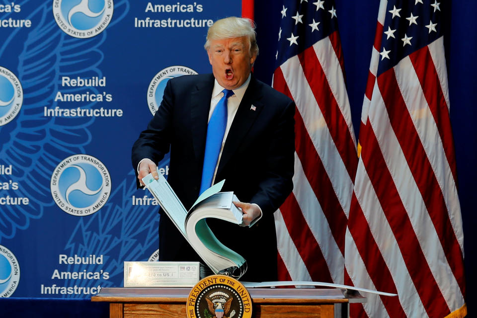 <span class="s1">President Trump shows off a binder with highway permitting documents while discussing infrastructure improvements on June 9. (Photo: Jonathan Ernst/Reuters)</span>