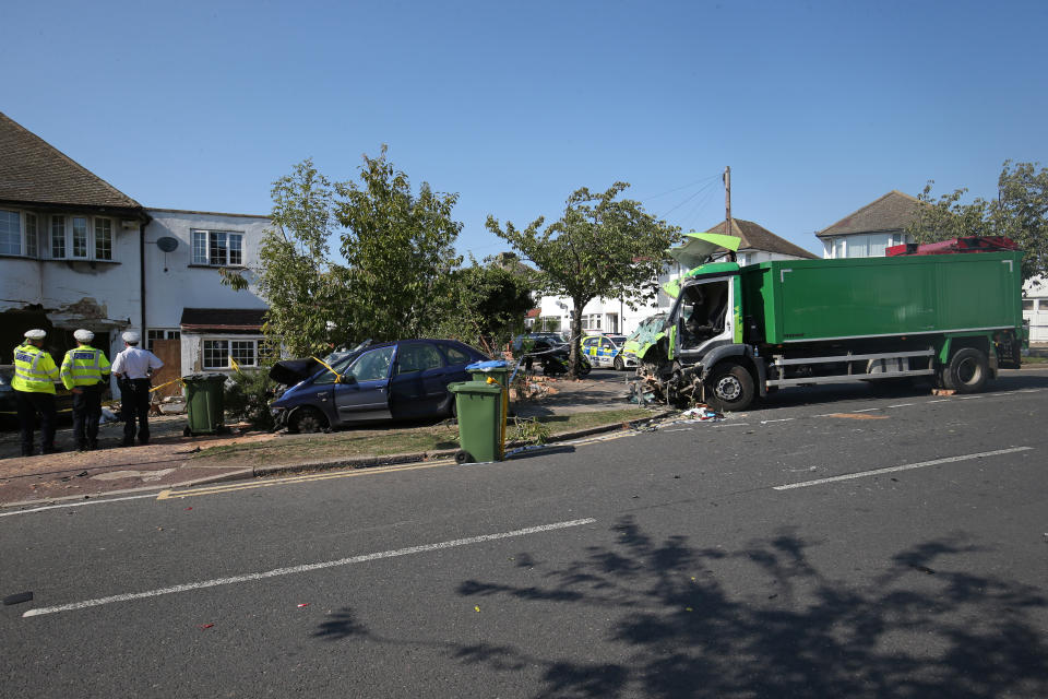 Police at the scene of a collision in Broad Walk, Kidbrooke, south-east London, where the driver of a lorry which hit two cars before crashing into a house has died and an 11-year-old child is in a life-threatening condition in hospital.