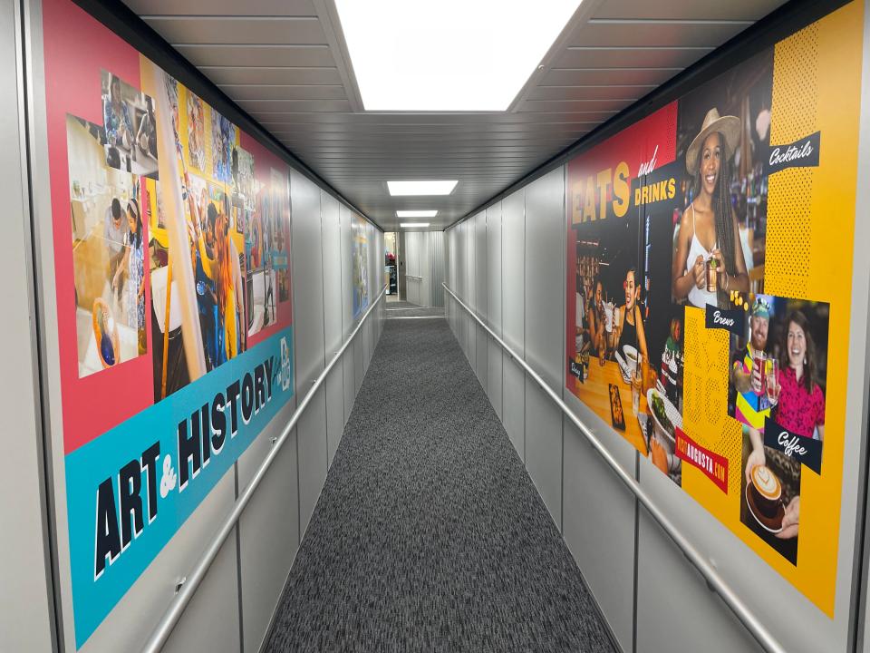 Augusta-themed murals decorate either side of the new carpeted Gate 4 passenger bridge as it extends back to the terminal at Augusta Regional Airport, Friday, May 17, 2024.