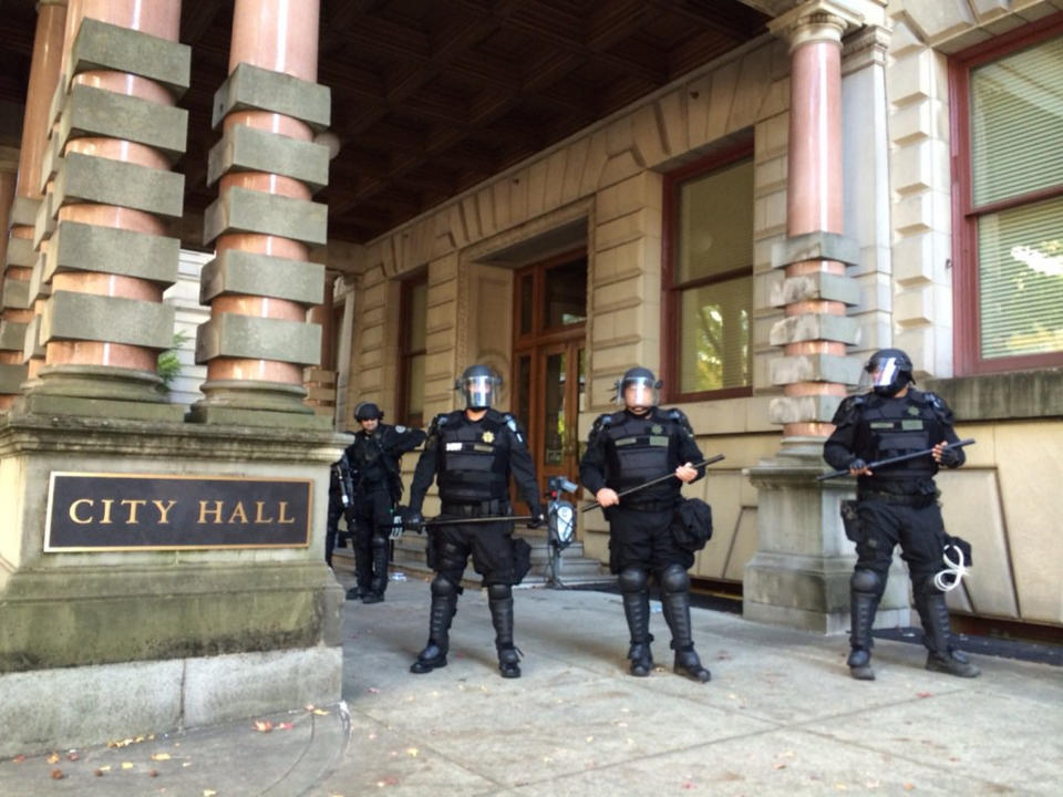 FILE - In this Oct. 12, 2016, file photo, Portland police stand guard outside of City Hall in Portland, Ore., after protestors disrupted a city council meeting, leading to arrests. The City Council approved an emergency ordinance Wednesday, March 15, 2017, that would allow the city to eject disruptive protesters and ban them from council chambers for up to 60 days in some cases. (Brad Schmidt/The Oregonian via AP, File)