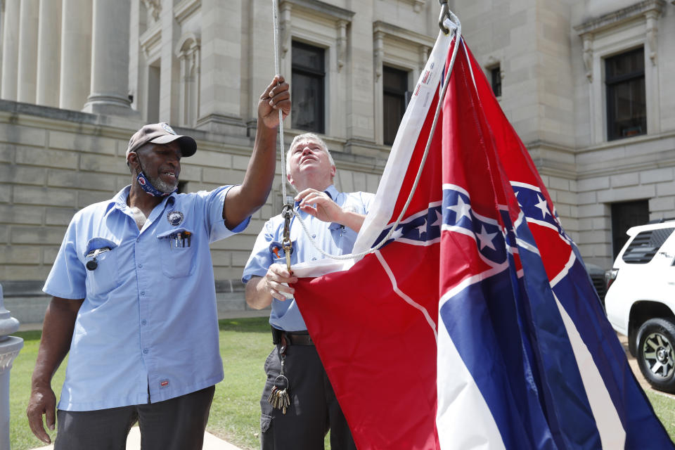 Mississippi Department of Finance and Administration employees Willie Townsend, left, and Joe Brown, attach a couple of Mississippi state flags to the harness before raising them over the Capitol grounds in Jackson, Miss., Tuesday, June 30, 2020. The two men raised about 100 flags, provided by the Secretary of State's office, for people or organizations that purchased a state flag that flew over the grounds. Gov. Tate Reeves will sign a bill that evening retiring the last state flag with the Confederate battle emblem during a ceremony at the Governor's Mansion. Upon the governor signing the bill, the flag will lose its official status. (AP Photo/Rogelio V. Solis)