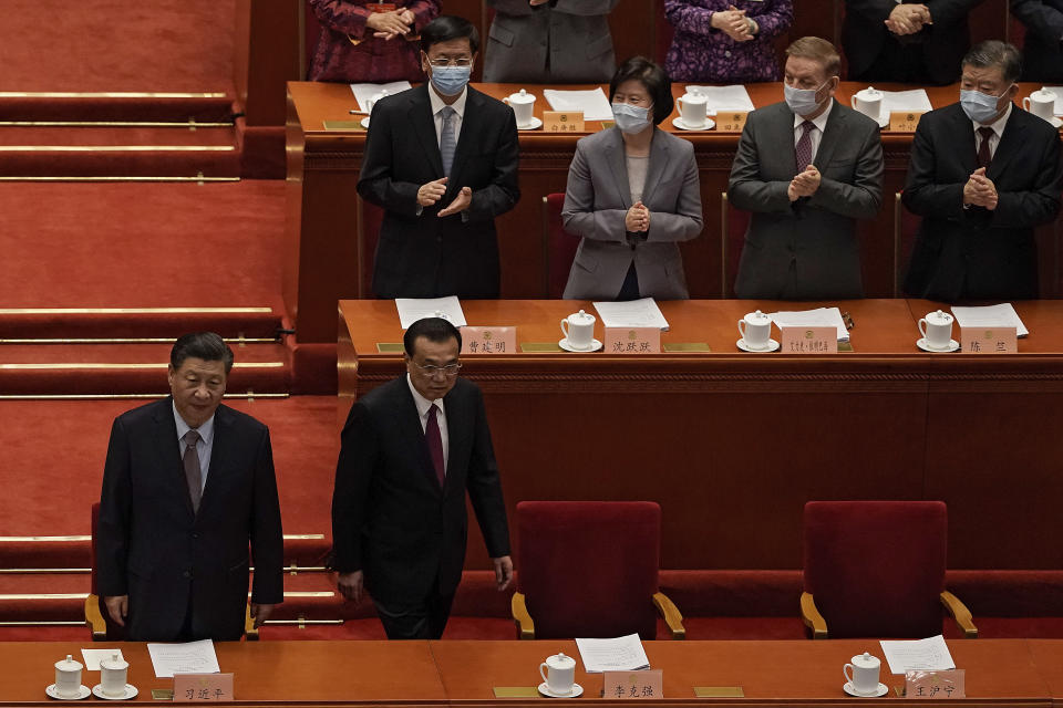 Delegates wearing face masks to help curb the spread of the coronavirus applaud as Chinese President Xi Jinping, left, and his Premier Li Keqiang arrive for the opening session of Chinese People's Political Consultative Conference (CPPCC) at the Great Hall of the People in Beijing, Thursday, March 4, 2021. (AP Photo/Andy Wong)