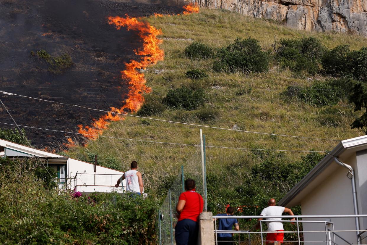 Residents look at flames burning in Capaci, near Palermo, in Sicily, southern Italy (AP)