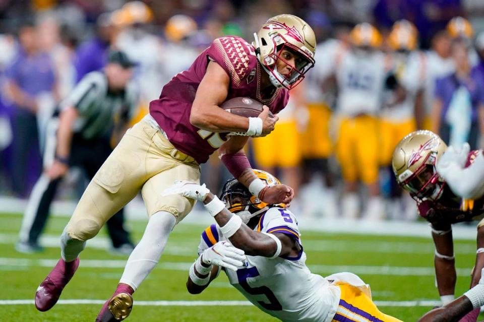 Florida State quarterback Jordan Travis (13) tries to avoid LSU safety Jay Ward (5) during their game in New Orleans on Sept. 4, 2022. Gerald Herbert/AP