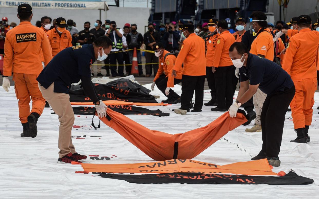 Members of the Indonesian Search and Rescue (SAR) team carry body parts of passengers on board the Sriwijaya Air flight SJ-182 at Tanjung Priok Port - Xinhua / Alamy Live News