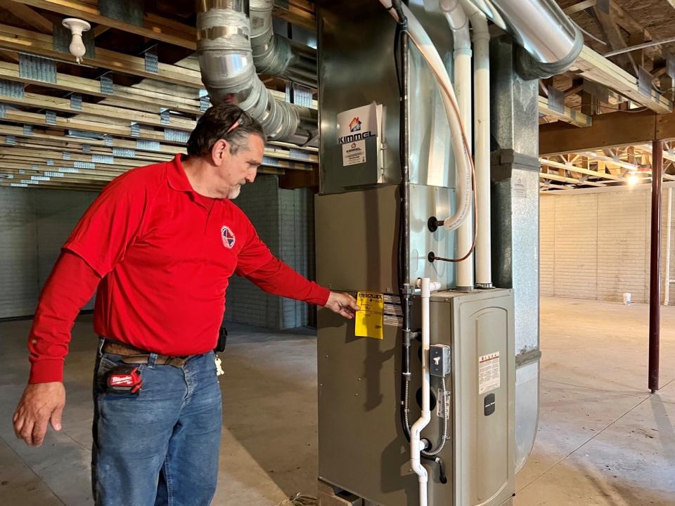 Four Cities Compact carpentry teacher Chris Kallai shows off an energy-efficient heater in a Wadsworth home built by students.