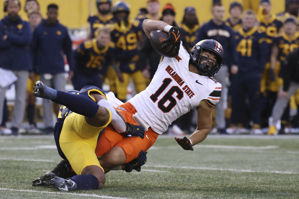 Oklahoma State's Josiah Johnson (16) is tackled after a catch by West Virginia's Jairo Favors, left, during the second half of an NCAA college football game Saturday, Oct. 21, 2023, in Morgantown, W.Va. (AP Photo/Chris Jackson)