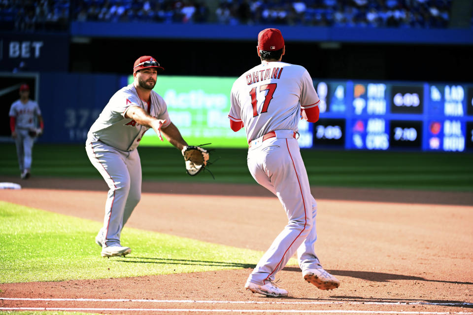 Los Angeles Angels first baseman Mike Ford, left, tosses a fielded grounder off the bat of Toronto Blue Jays Raimel Tapia to pitcher Shohei Ohtani during the fifth inning of a baseball game, Saturday, Aug. 27, 2022 in Toronto. (Jon Blacker/The Canadian Press via AP)