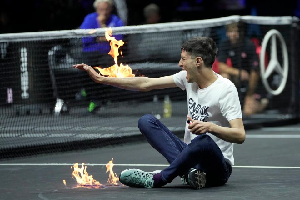 A protester lights his arm on fire on the court on day one of the Laver Cup (Kin Cheung/AP) (AP)