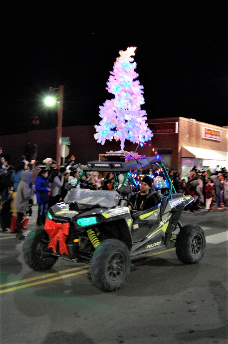 An illuminated Christmas tree rides atop a four-wheel-drive vehicle during the Christmas Parade down Main Street through downtown Farmington on Dec. 2, 2021.