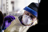 Seattle firefighter Bill Dennis reaches in to take a sample from a passenger in a car at a free COVID testing site Friday, Oct. 23, 2020, in Seattle. The United States is approaching a record for the number of new daily coronavirus cases in the latest ominous sign about the disease's grip on the nation, as states from Connecticut to Idaho reel under the surge. (AP Photo/Elaine Thompson)