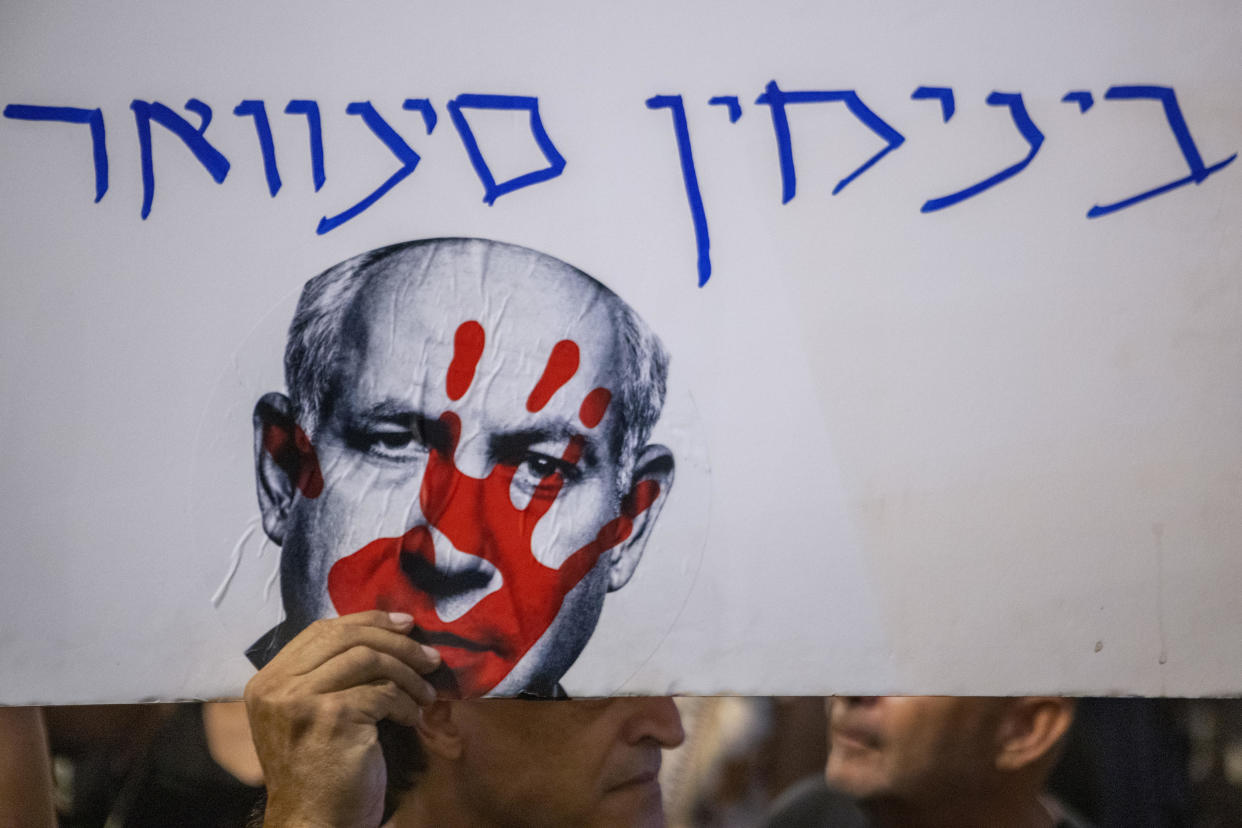 An Israeli protester carries a poster reading in Hebrew 