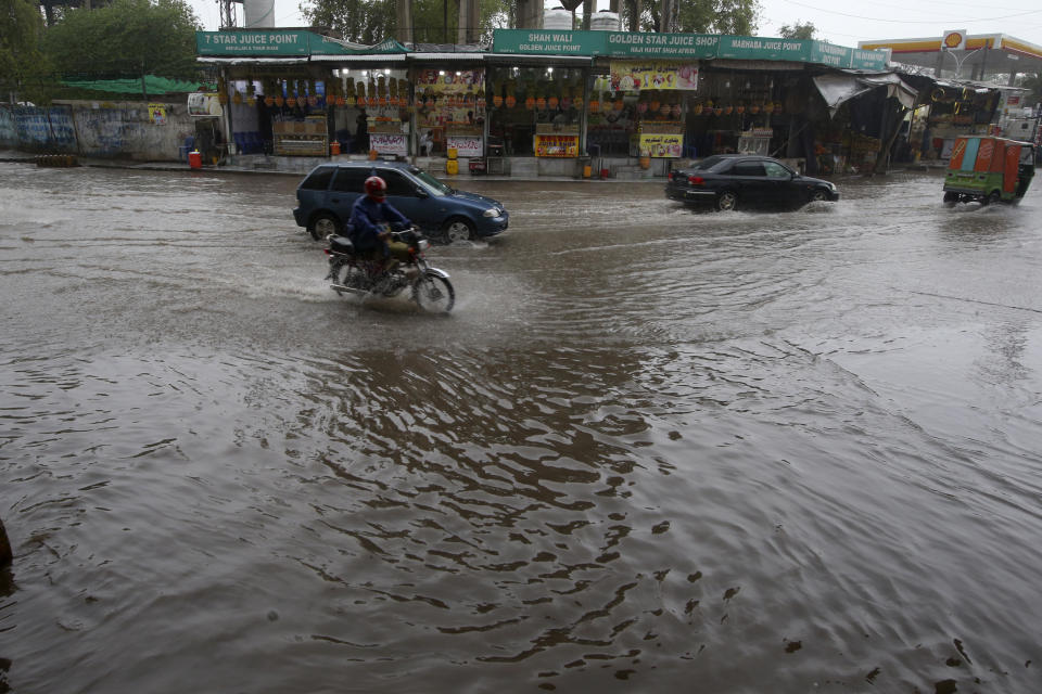 A motorcyclist and car drivers drive through a flooded road caused by heavy rain in Peshawar, Pakistan, Monday, April 15, 2024. Lightening and heavy rains killed dozens of people, mostly farmers, across Pakistan in the past three days, officials said Monday, as authorities declared a state of emergency in the country's southwest following an overnight rainfall to avoid any further casualties and damages. (AP Photo/Muhammad Sajjad)