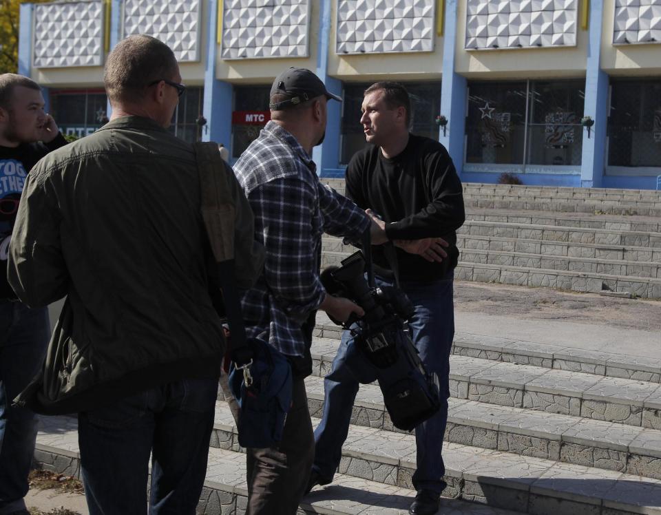 Belarus plainclothes security officer, right, holds a camera, he took away from a journalist, during in Minsk , Tuesday, Sept. 18, 2012. Associated Press photographer Sergei Grtts was beaten and briefly detained by plainclothes security officers in the Belarusian capital. Sergei Grits says he was among eight journalists covering a protest by four opposition activists calling for a boycott of this weekend's parliamentary elections when plainclothes security officers attacked them in downtown Minsk.(AP Photo/Sergei Grits)