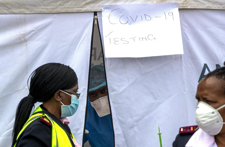 FILE - In this Wednesday, April 8, 2020 file photo, health workers wear personal protective gear inside a COVID-19 testing tent in Lenasia, south of Johannesburg, South Africa. On Friday, April 10, 2020, The Associated Press reported on stories circulating online incorrectly asserting that former U.S. President Barack Obama said that he would not “allow white people to kill Africans with their toxic vaccines.” The fabricated claim shared across social media grew out of a French TV segment where two doctors suggested that a tuberculosis vaccine be tested in Africa in trials to fight the coronavirus. (AP Photo/Themba Hadebe)